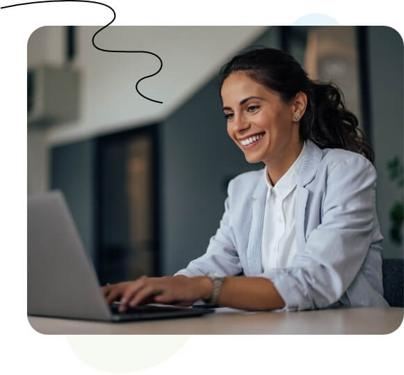 Une femme assise à un bureau, tapant sur un ordinateur portable devant un tableau blanc.