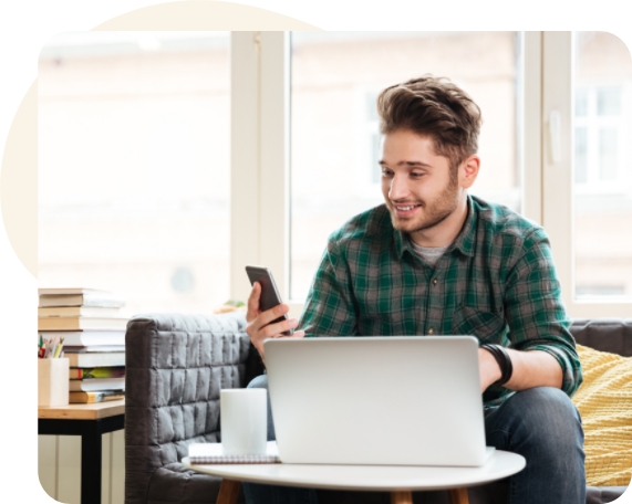 Man in front of laptop and checking phone